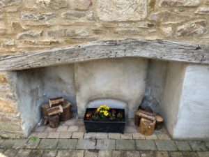 The old bakery fire place has been resurrected with a variety of flame coloured flowers, flanked by piles of logs