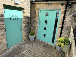 The Secret Garden entrance and toilet doors now framed by Cyprus evergreens and perenials